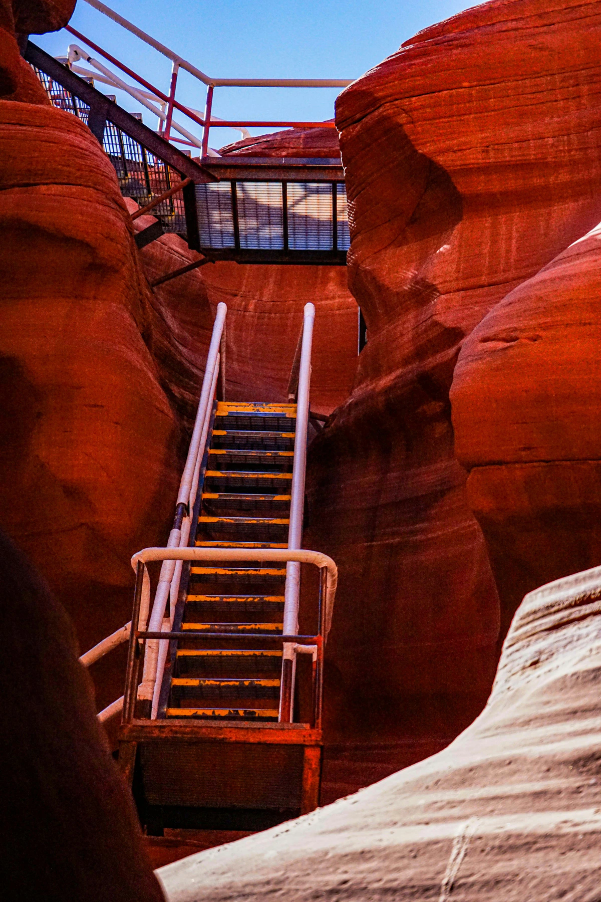 Metal stairs ascending between red sandstone walls in Lower Antelope Canyon
